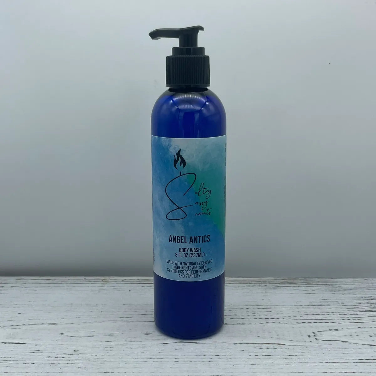 Front label view of a large 8-ounce blue pump bottle containing Sultry Sassy Scents "Angel Antics" Body Wash, showcasing the central brand logo design.