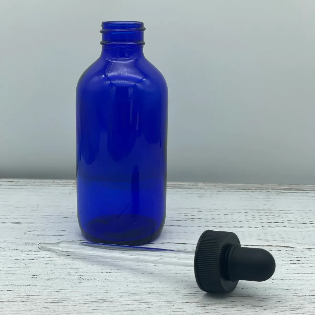 A blank 4-ounce cobalt blue glass bottle shown next to its black eye dropper attachment, serving as a placeholder image for concentrated diffuser oils.