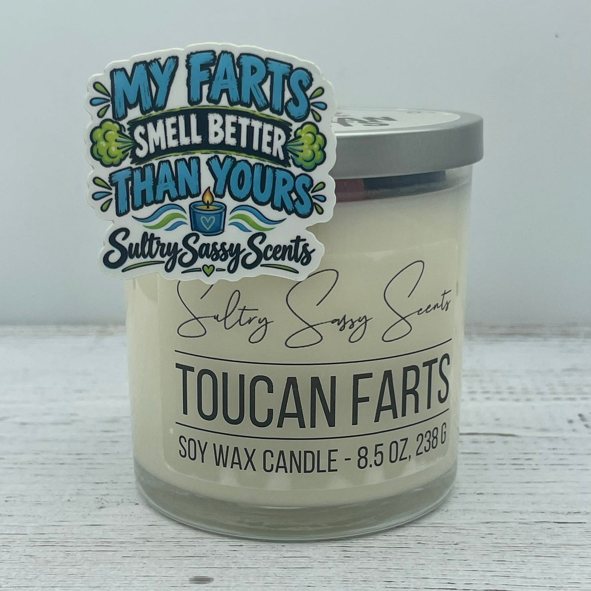 My farts smell better vinyl sticker styled next to a Toucan Farts jar candle