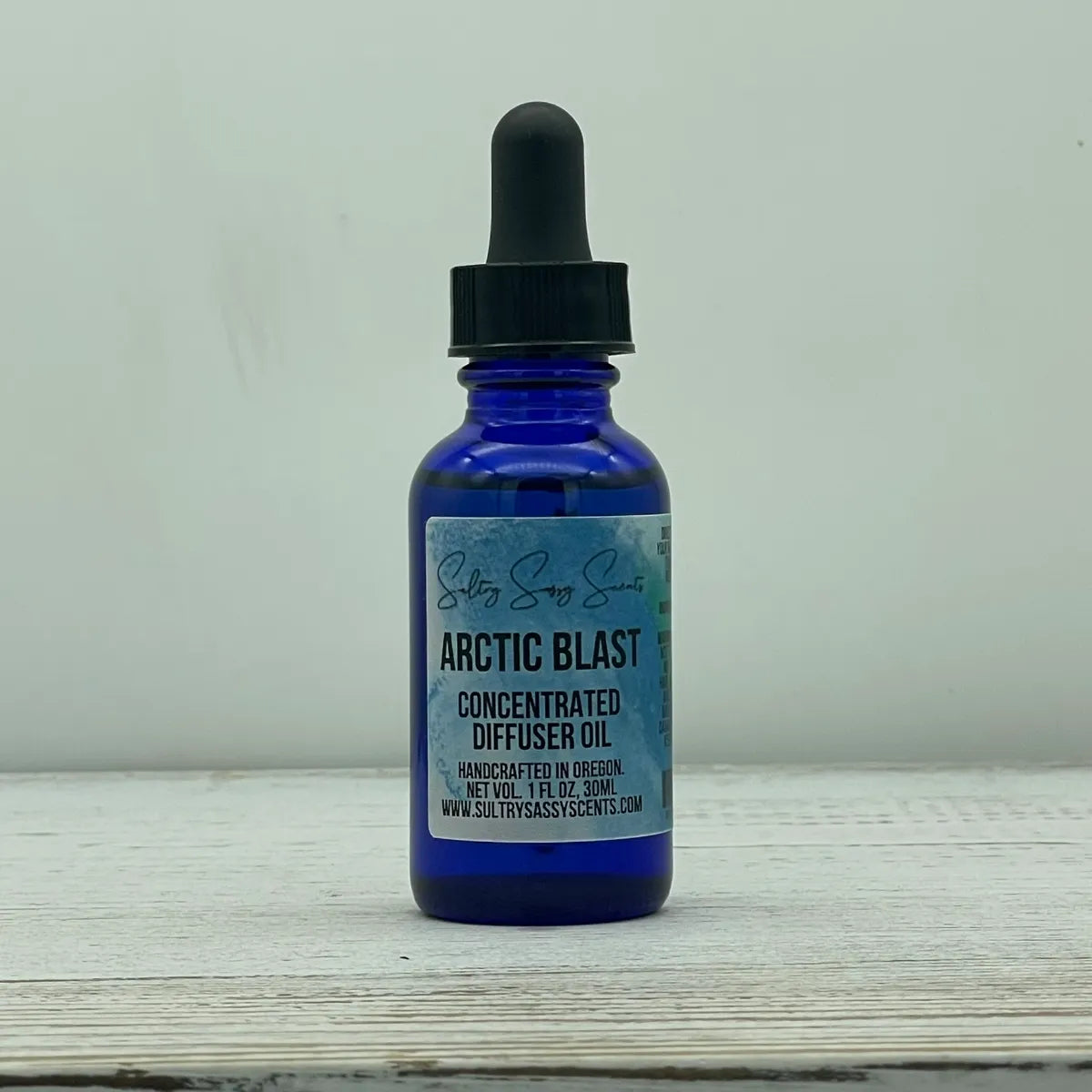 Front label view of a cobalt blue glass dropper bottle for Sultry Sassy Scents "Arctic Blast" Concentrated Diffuser Oil, showing handcrafted in Oregon details.