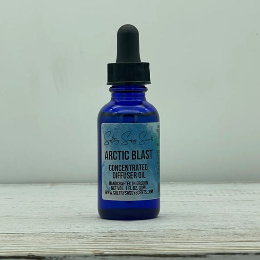 Front label view of a cobalt blue glass dropper bottle for Sultry Sassy Scents "Arctic Blast" Concentrated Diffuser Oil, showing handcrafted in Oregon details.