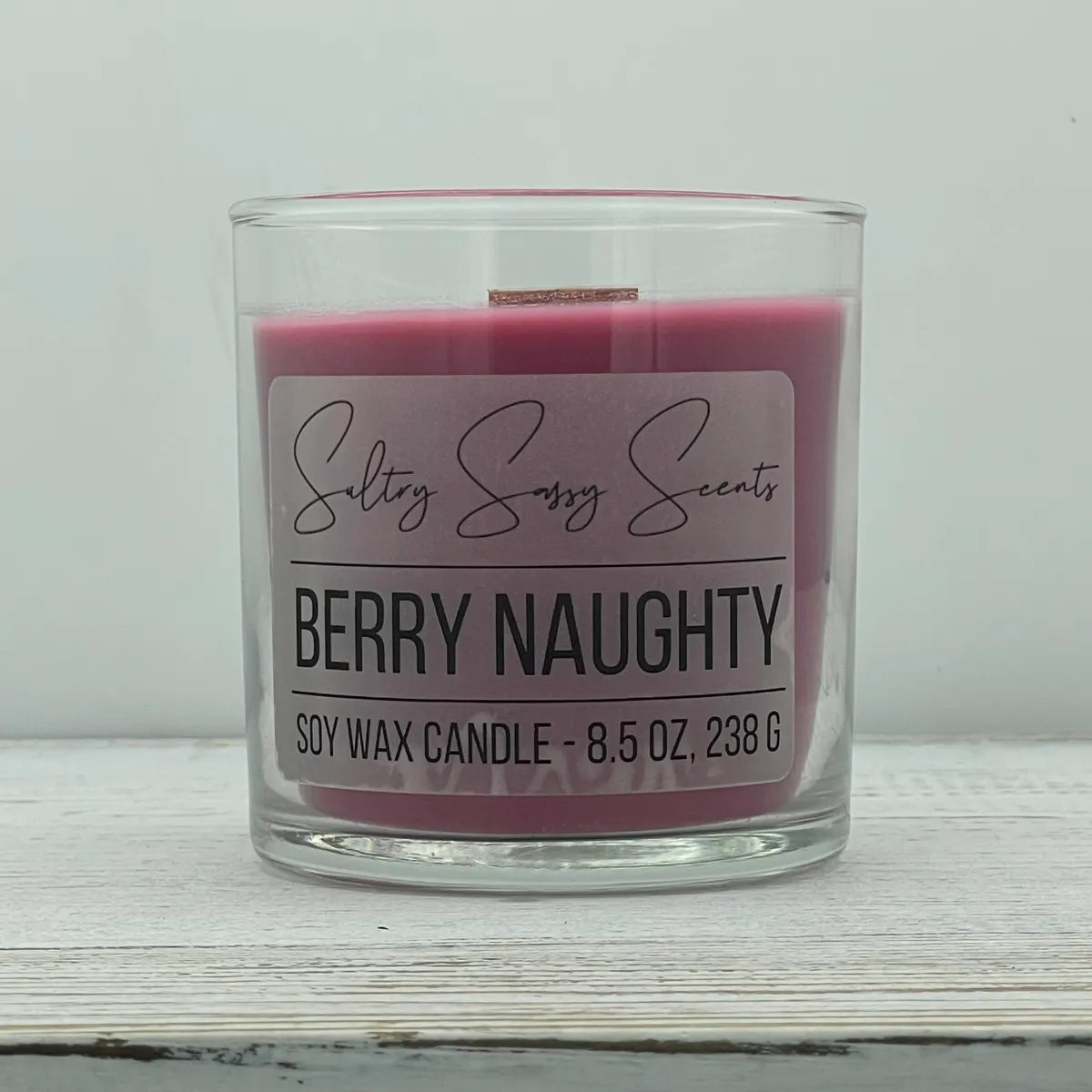 An 8.5-ounce jar of Sultry Sassy Scents "Berry Naughty" soy wax candle featuring a rich dark pink wax color, centered against a light gray background.