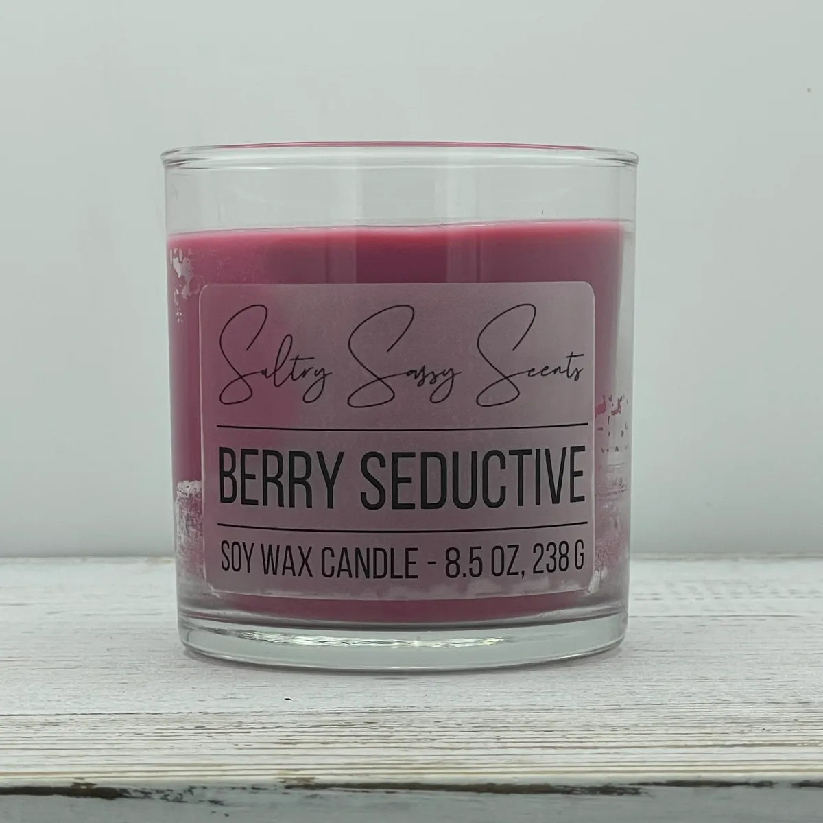 An 8.5-ounce jar of Sultry Sassy Scents "Berry Seductive" soy wax candle featuring a vibrant magenta pink wax color, showcasing the clean typography label layout.