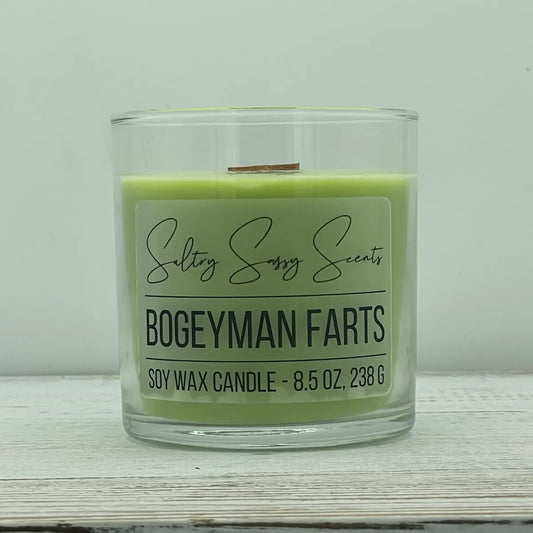 An 8.5-ounce jar of Sultry Sassy Scents "Bogeyman Farts" soy wax candle featuring a light mint green wax color and a wooden wick, centered on a white wood background.