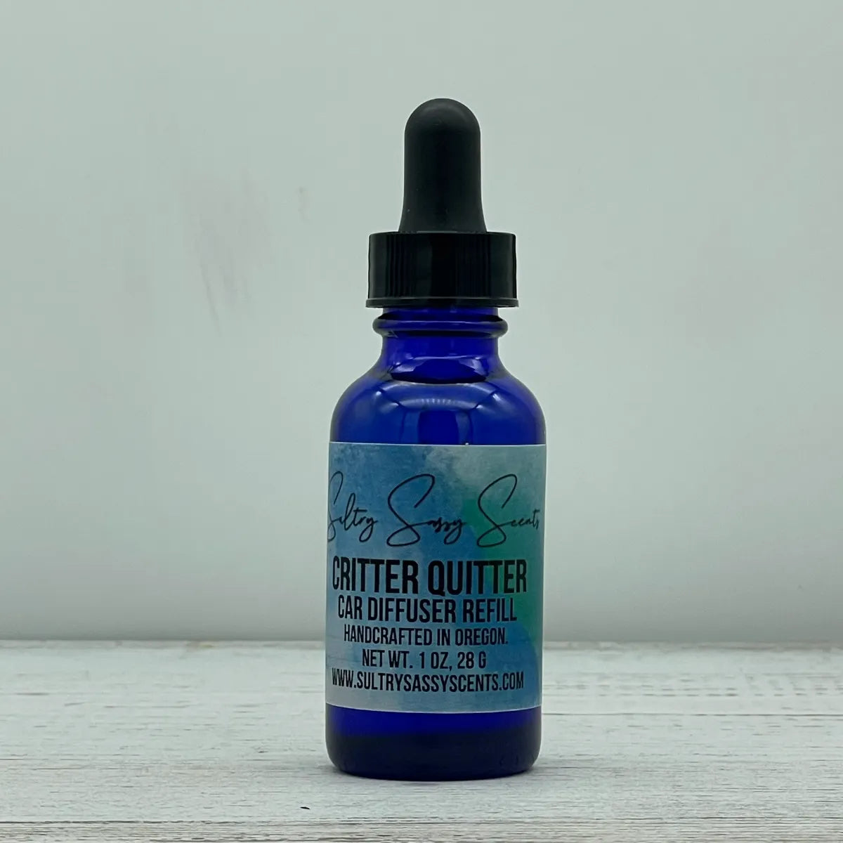 Front label view of a blue glass dropper bottle for Sultry Sassy Scents "Critter Quitter" Car Diffuser Refill, showcasing the clean typography layout.