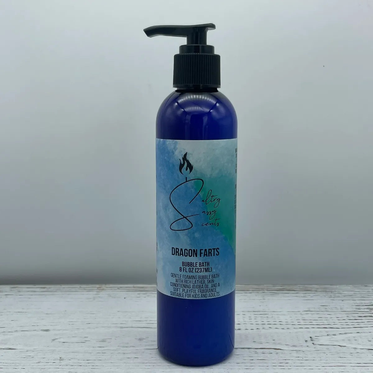 Front label view of a large 8-ounce blue pump bottle containing Sultry Sassy Scents "Dragon Farts" Bubble Bath, highlighting the watercolor brand label layout.