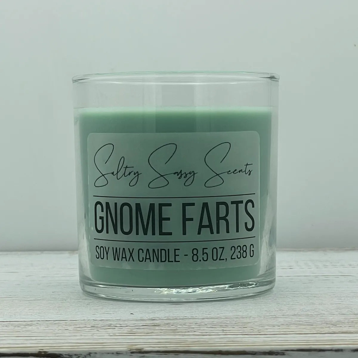  An 8.5-ounce clear glass jar of Sultry Sassy Scents "Gnome Farts" soy wax candle displaying a soft pastel mint green wax color, centered against a light gray background.