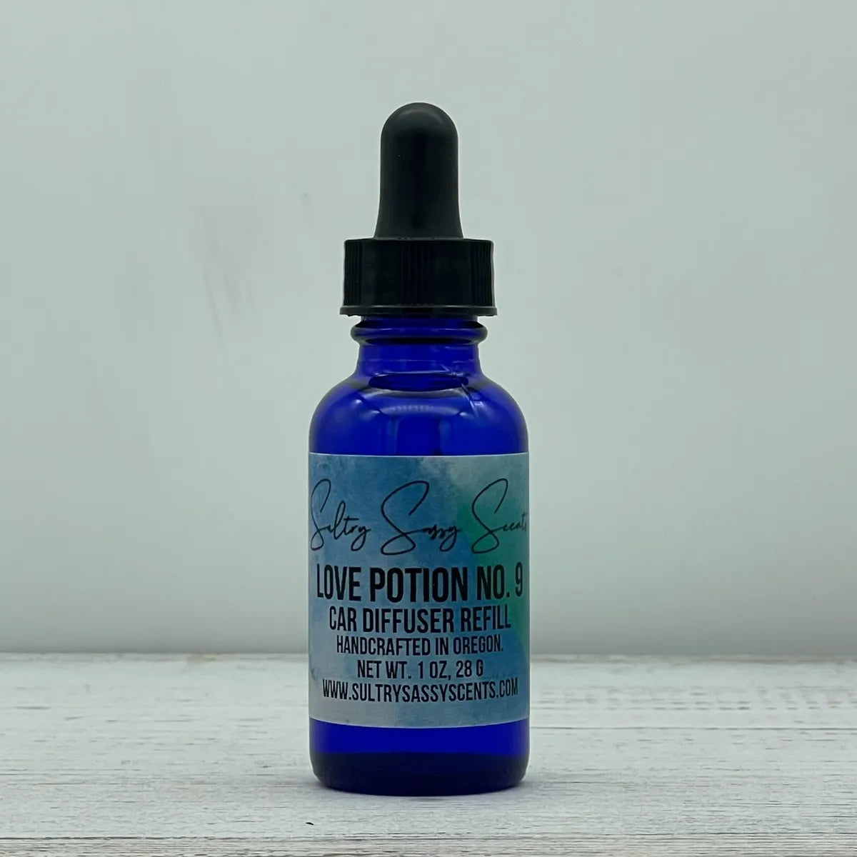 Front label view of a cobalt blue glass dropper bottle containing Sultry Sassy Scents "Love Potion No. 9" Car Diffuser Refill, showcasing the clean typography layout.