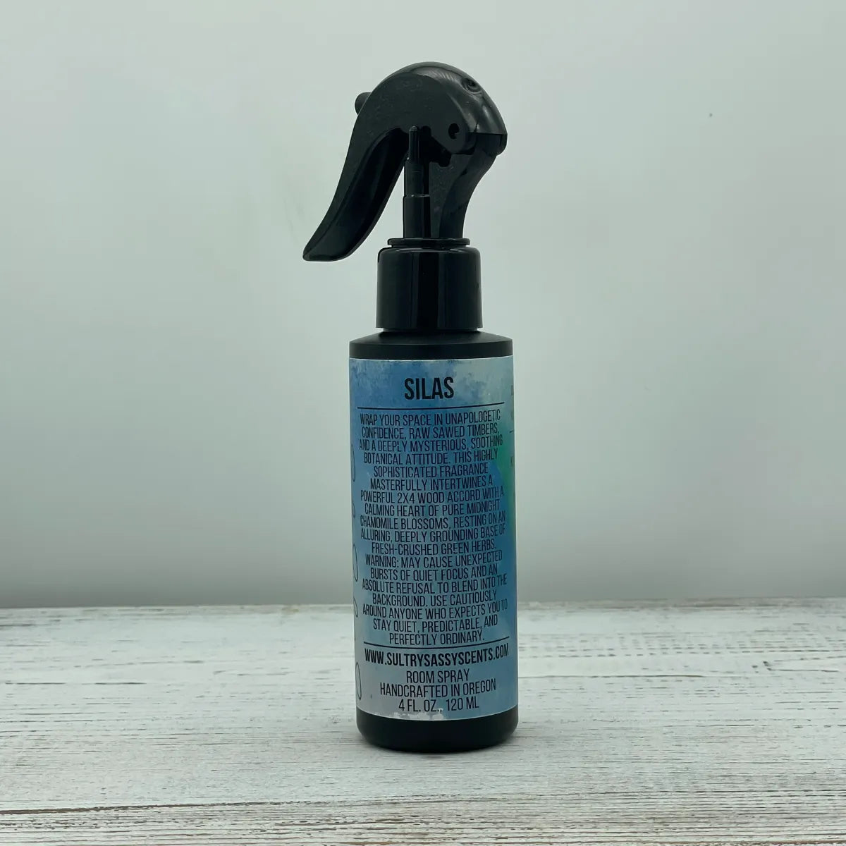 Front label of a black spray bottle for Sultry Sassy Scents "Silas" Room Spray, showcasing a bold, clean typography design with a detailed fragrance description.