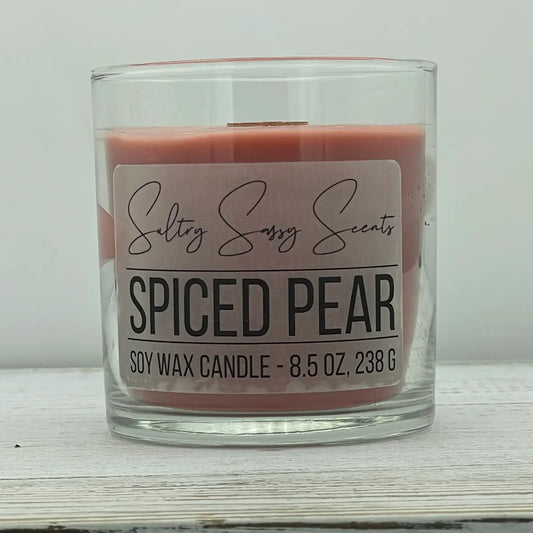 An 8.5-ounce clear glass jar of Sultry Sassy Scents "Spiced Pear" soy wax candle showcasing a soft terracotta rust-pink wax color with a flat wooden wick.