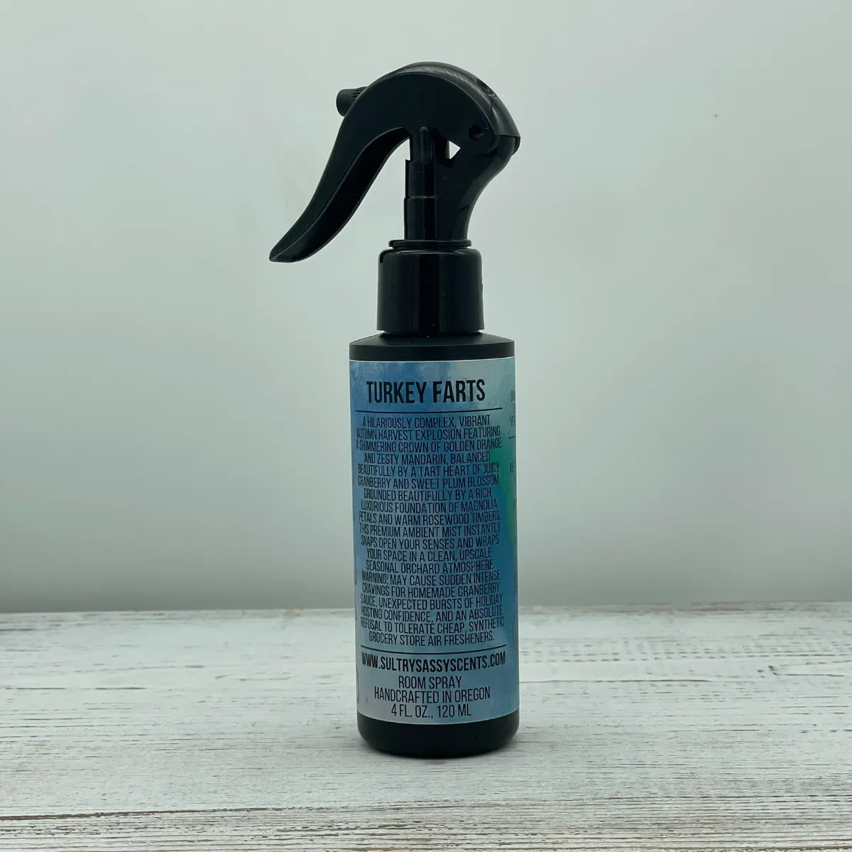 Front label of a black spray bottle for Sultry Sassy Scents "Turkey Farts" Room Spray, displaying an autumn-themed description of orange, mandarin, cranberry, and plum scents.