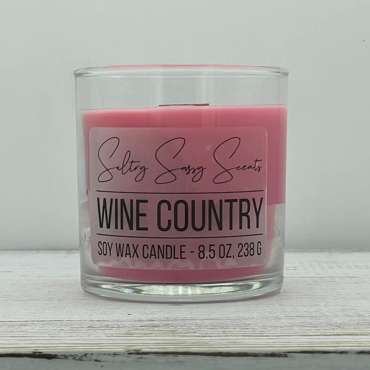 An 8.5-ounce clear glass jar of Sultry Sassy Scents "Wine Country" soy wax candle featuring a soft dusty rose pink wax color, centered against a clean light background.