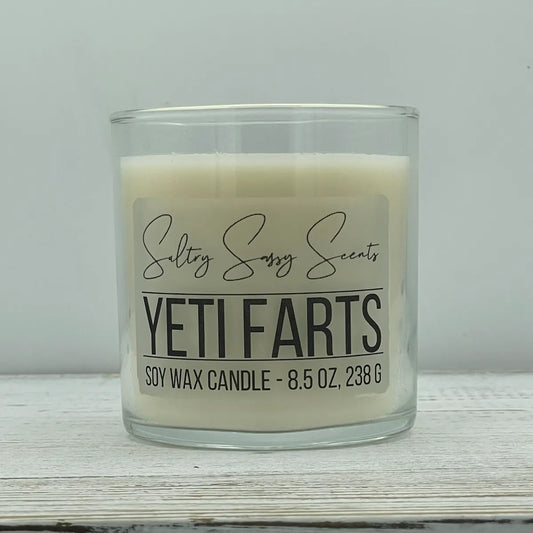 An 8.5-ounce clear glass jar of Sultry Sassy Scents "Yeti Farts" soy wax candle featuring a clean, solid white wax color, centered on a light wood surface.